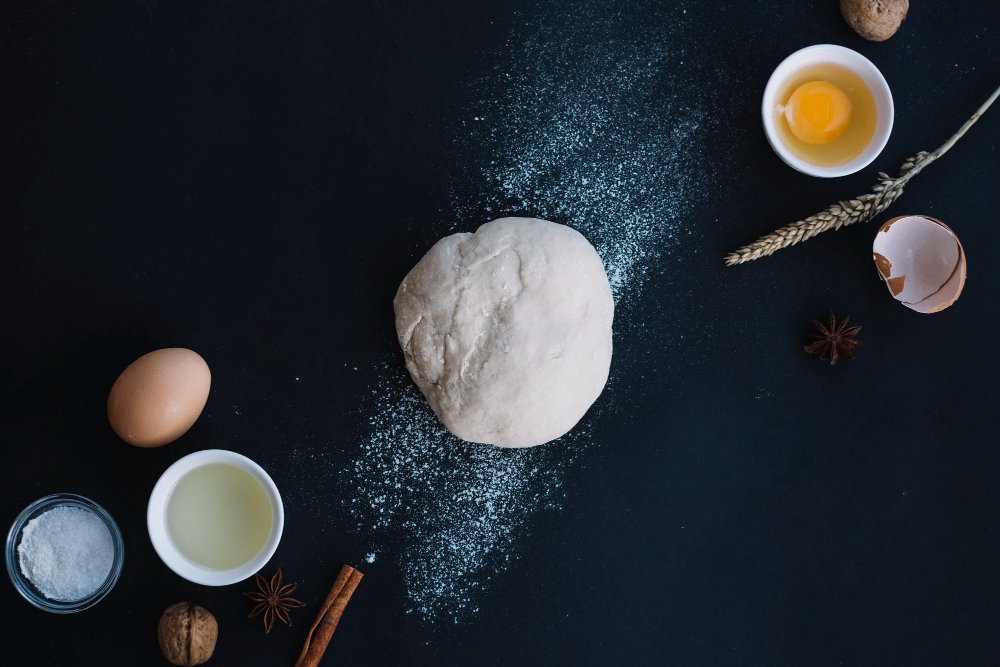 high-angle-view-dough-with-baking-ingredients-black-backdrop